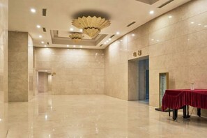 A spacious, well-lit lobby with a marble floor, a red table, and a decorative ceiling light fixture. - Grace Hotel (Suzhou)