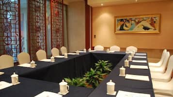 A conference room with a long table, chairs, and a decorative screen.