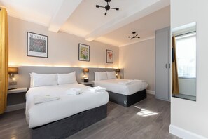 Una camera d'albergo con due letti, un grande specchio e opere d'arte alle pareti.