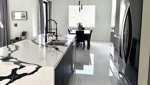 Una cocina moderna con encimera de mármol, electrodomésticos de acero inoxidable y una zona de comedor con mesa y sillas.