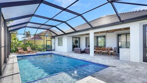 Zona de piscina cubierta con patio, sillas de descanso y un conjunto de comedor.