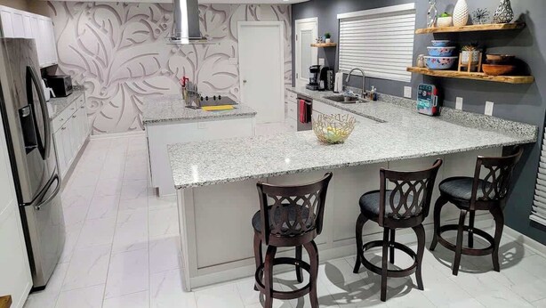 A modern kitchen with a large island, bar stools, a built-in oven, and a decorative backsplash. - Downtown Savannah Oasis w Heated Pool & Spa (Savannah)