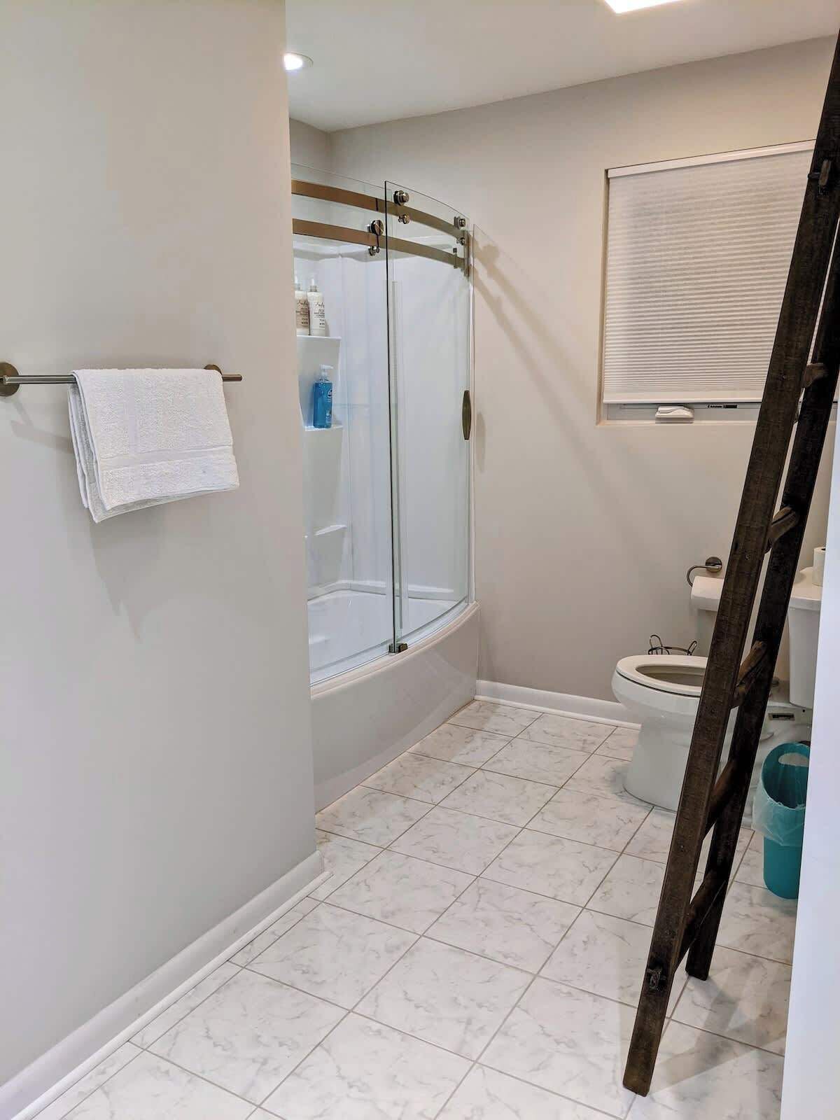 A bathroom with a glass shower enclosure, a toilet, and a towel rack.