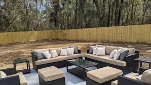 An outdoor seating area with a sectional sofa, ottomans, and a coffee table. - Downtown Savannah Oasis w Heated Pool & Spa (Savannah)