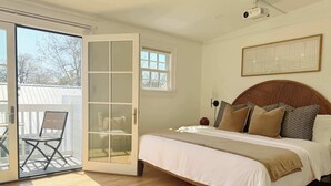 A bedroom with a bed, a sliding glass door to a balcony, a small window, and a projector on the ceiling. - Spacious 3-Floor Downtown Retreat - Prime Location (Savannah)
