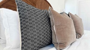 A bed with a wooden headboard, white bedding, and patterned pillows. - Spacious 3-Floor Downtown Retreat - Prime Location (Savannah)