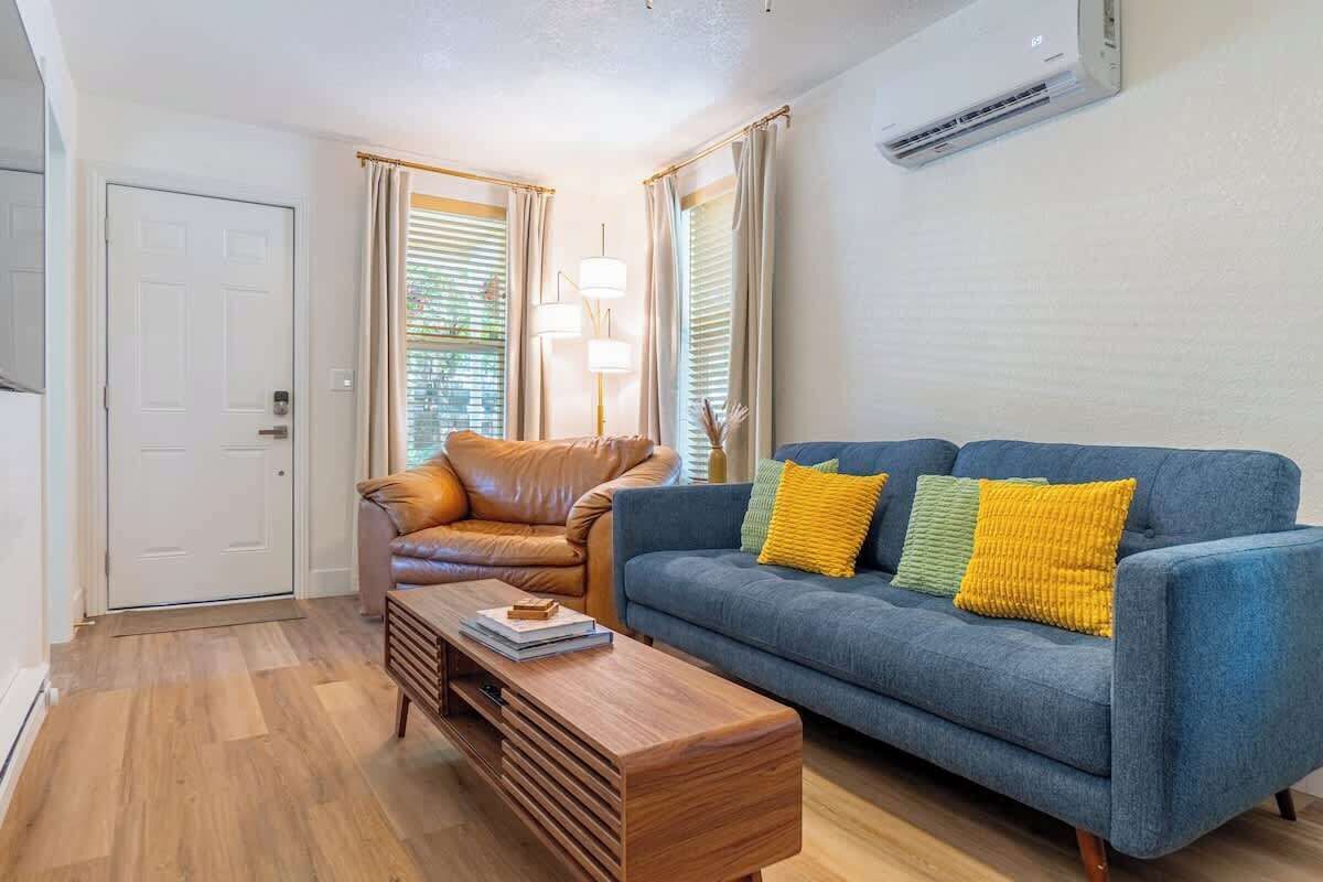Een moderne woonkamer met een blauwe bank, een bruine leren fauteuil en een houten salontafel.