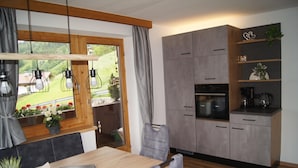Une cuisine moderne avec des meubles gris, un plan de travail en bois et un coin repas comprenant une table et des chaises.