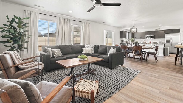 A modern living room with a sofa, coffee table, and chairs, a dining area with a table and chairs, and a kitchen with appliances. - Spacious 6BR - Sleeps 22 - Hot Tub & Pool Access (Meridian)