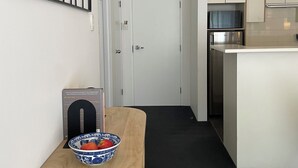 A modern kitchen with white cabinetry, a stainless steel refrigerator, and a black countertop.