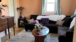 Una sala de estar acogedora con una mesa de centro de madera, dos sofás, una mesita auxiliar y una planta en maceta.