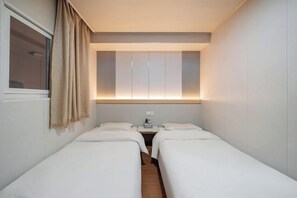 A hotel room with two single beds, a bedside table with a lamp, and a window with curtains. - Manfulou Hotel (Shanghai Jing'ansi) (Shanghai)