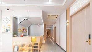 Un pasillo moderno de hotel con una recepción, un reloj y un equipo de aire acondicionado instalado en la pared.
