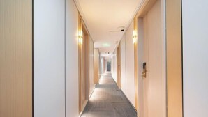 Un largo y estrecho pasillo de hotel con paneles de madera en las paredes y suelo alfombrado.