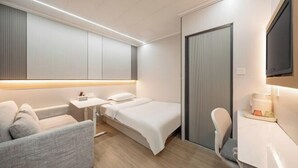 Una habitación de hotel moderna con cama, sofá, escritorio y televisión.