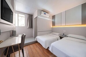 A hotel room with two beds, a desk, a chair, a TV, and an air conditioning unit. - Manfulou Hotel (Shanghai Jing'ansi) (Shanghai)