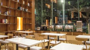 A restaurant with white tables and chairs, a wooden bookshelf, and a view of greenery outside. - Xindi Hotel (Guangzhou Cultural Tourism City Huaguoshan Subway Station) (Guangzhou)