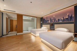 A modern hotel room with a cityscape view, a large bed, a seating area, and a walk-in closet.
