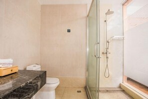 Un baño con inodoro, ducha y encimera de mármol con una caja de pañuelos.