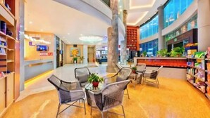 A spacious lobby with a curved ceiling, seating area with tables and chairs, and a large central column. - Xindi Hotel (Guangzhou Cultural Tourism City Huaguoshan Subway Station) (Guangzhou)