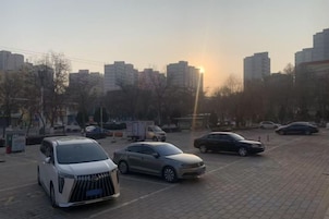 A parking lot with multiple cars and buildings in the background.