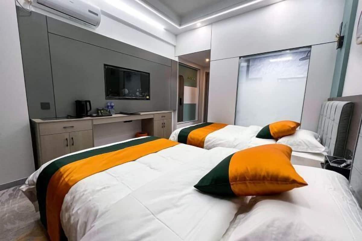 Une chambre d’hôtel avec deux lits, une télévision, un bureau et un miroir.