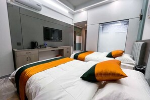 Une chambre d’hôtel avec deux lits, une télévision, un bureau et un miroir.