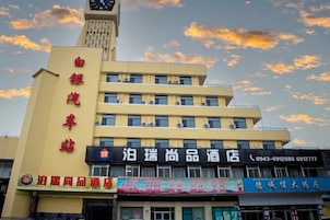 A multi-story building with a clock tower, multiple storefronts, and a clear sky with clouds.