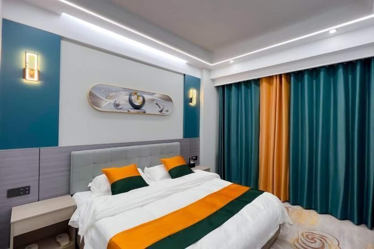Une chambre d’hôtel avec un lit, des tables de chevet, un luminaire fixé au mur et une fenêtre avec des rideaux.