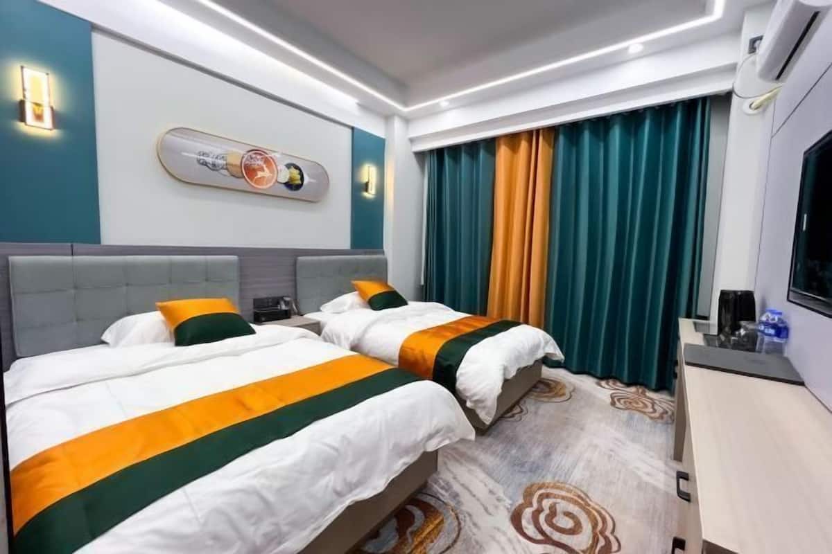 Une chambre d’hôtel avec deux lits, une télévision, un bureau et une œuvre d’art accrochée au mur.