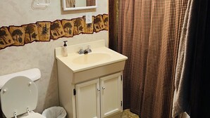 A bathroom with a toilet, sink, mirror, and shower curtain.