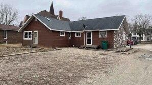A two-story house with a sloped roof, a front porch, and a driveway.