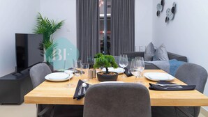 A dining area with a table set for two, a bonsai tree centerpiece, and a modern decor style. - Bloomfields 1BR Azizi Gardens Meydan (Dubai)