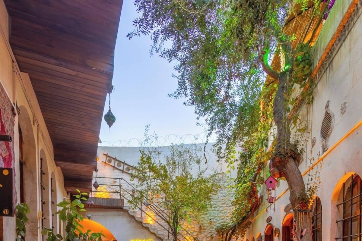 A courtyard with stone flooring, outdoor seating, and greenery.