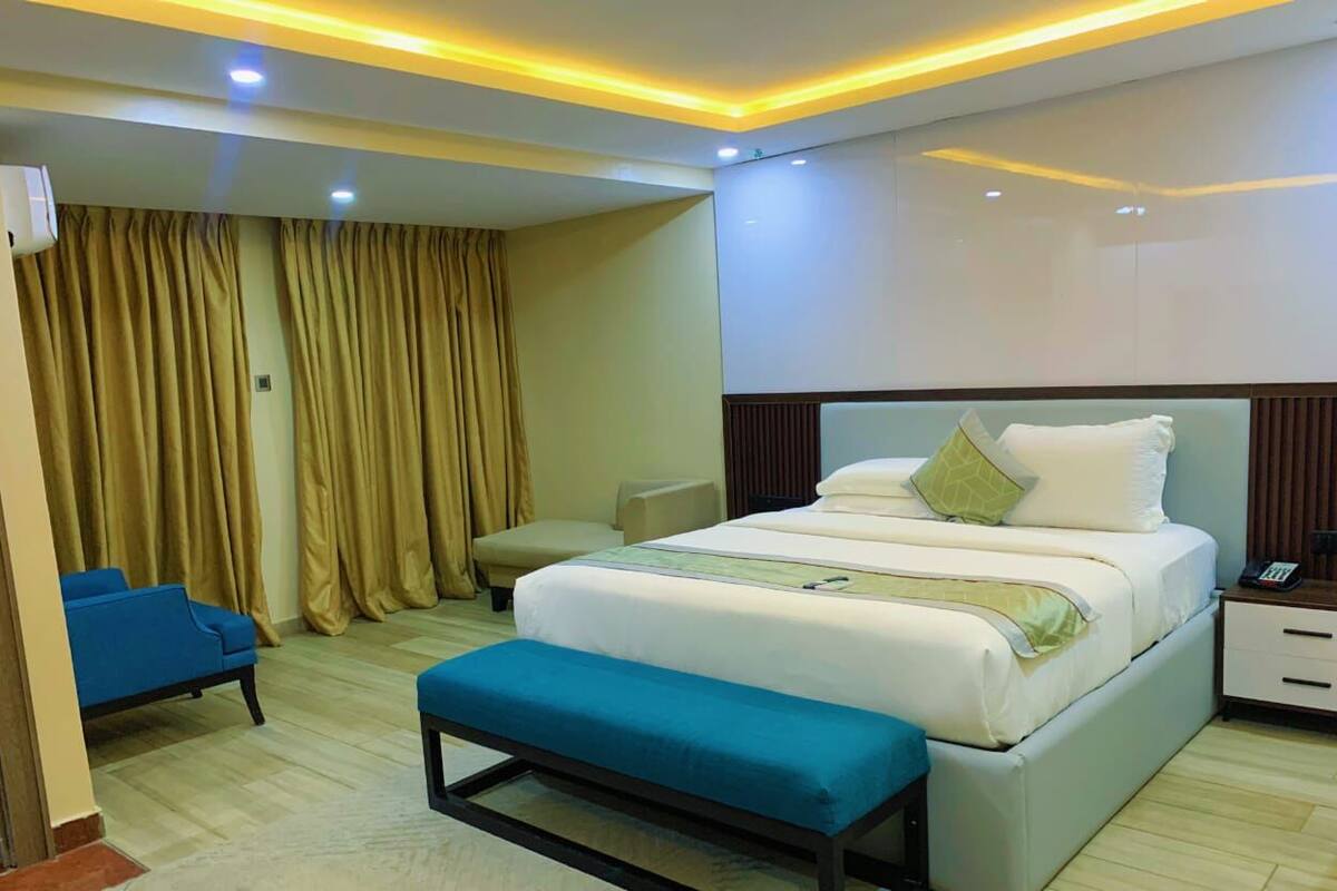 Une chambre d’hôtel moderne avec un grand lit, une table de chevet et un banc.