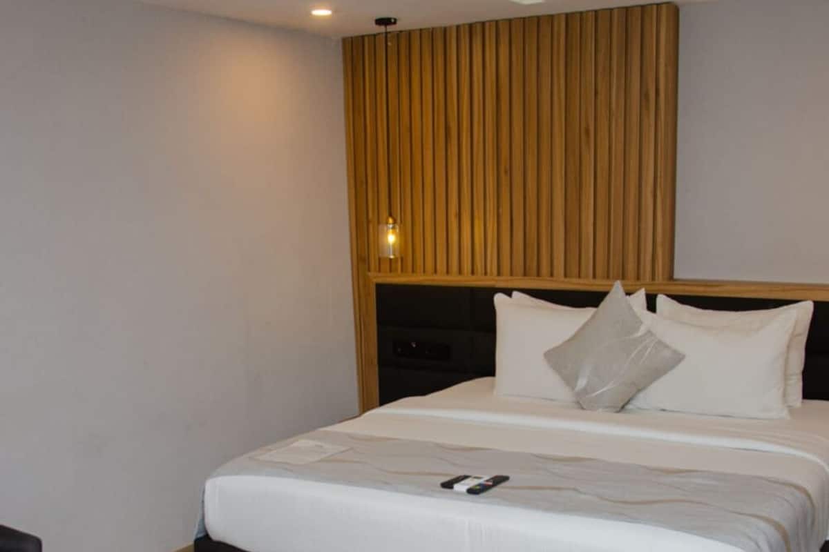 Une chambre d’hôtel moderne avec un grand lit, une tête de lit en bois et une petite table.