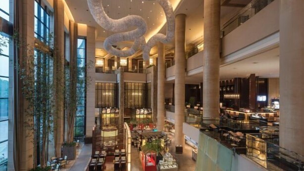 Un amplio vestíbulo de hotel con varios pisos, ventanas grandes y una escalera espiral central.