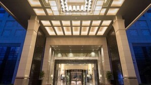 Entrada de hotel con diseño moderno, destacando una puerta de vidrio grande y un patrón geométrico en el techo.