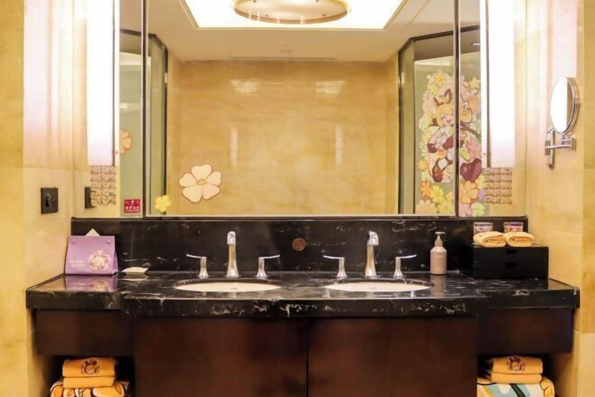 Ein Badezimmer mit zwei Waschbecken, einem großen Spiegel und einer Wandverzierung.