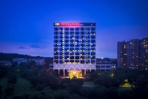 Un hotel de gran altura con fachada de diseño geométrico, ventanas iluminadas y una entrada destacada.