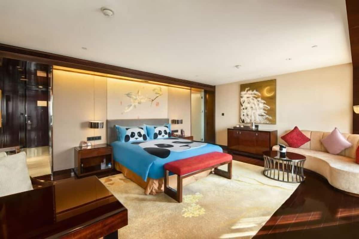 Ein modernes Hotelzimmer mit einem großen Bett, Nachttischen, einer Sitzecke und Kunstwerken an den Wänden.