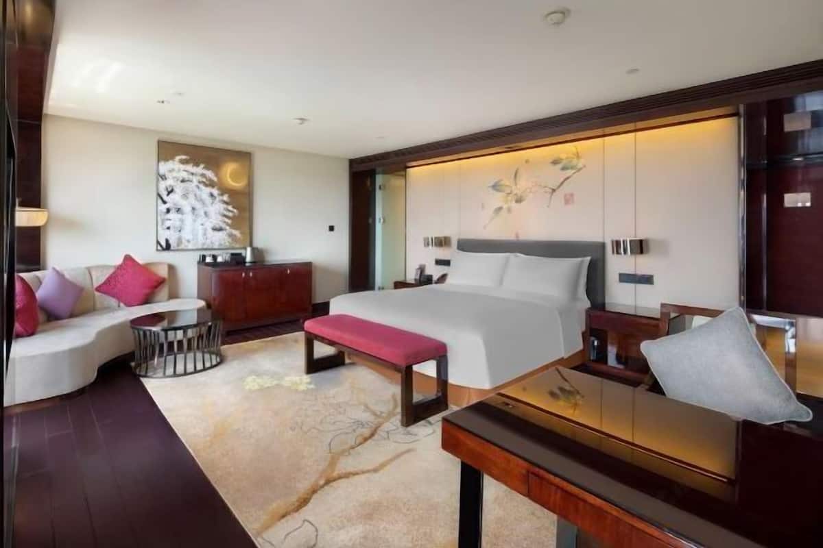 Ein modernes Hotelzimmer mit einem großen Bett, einer Couch, einem Schreibtisch und einer Wanddekoration.