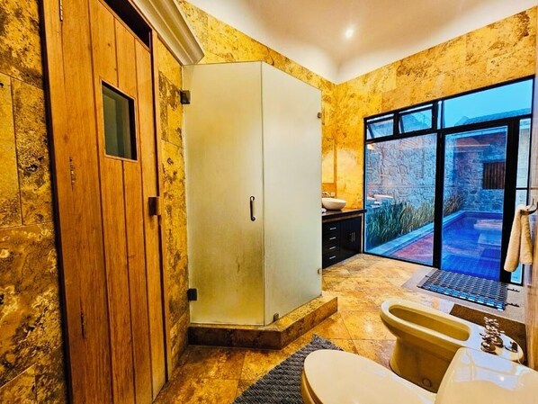 Un baño con bañera, inodoro y un ventanal que ofrece vistas a una piscina y zona exterior.
