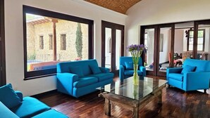 Un salón espacioso con ventanas amplias, sofás azules y una mesa de centro de vidrio.