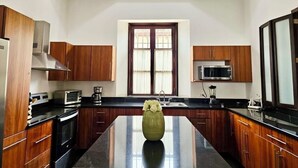 Una cocina moderna con armarios de madera, una isla central y un ventanal con cortinas.