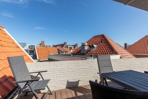 A rooftop terrace with a brick wall, metal chairs, and a table. - Apartment in Zeeland Near the Beach (Zoutelande)