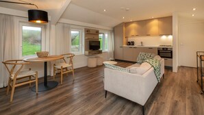 A modern, open-plan living area with a dining table, sofa, and kitchen. - Apartment in Zeeland Near the Beach (Zoutelande)