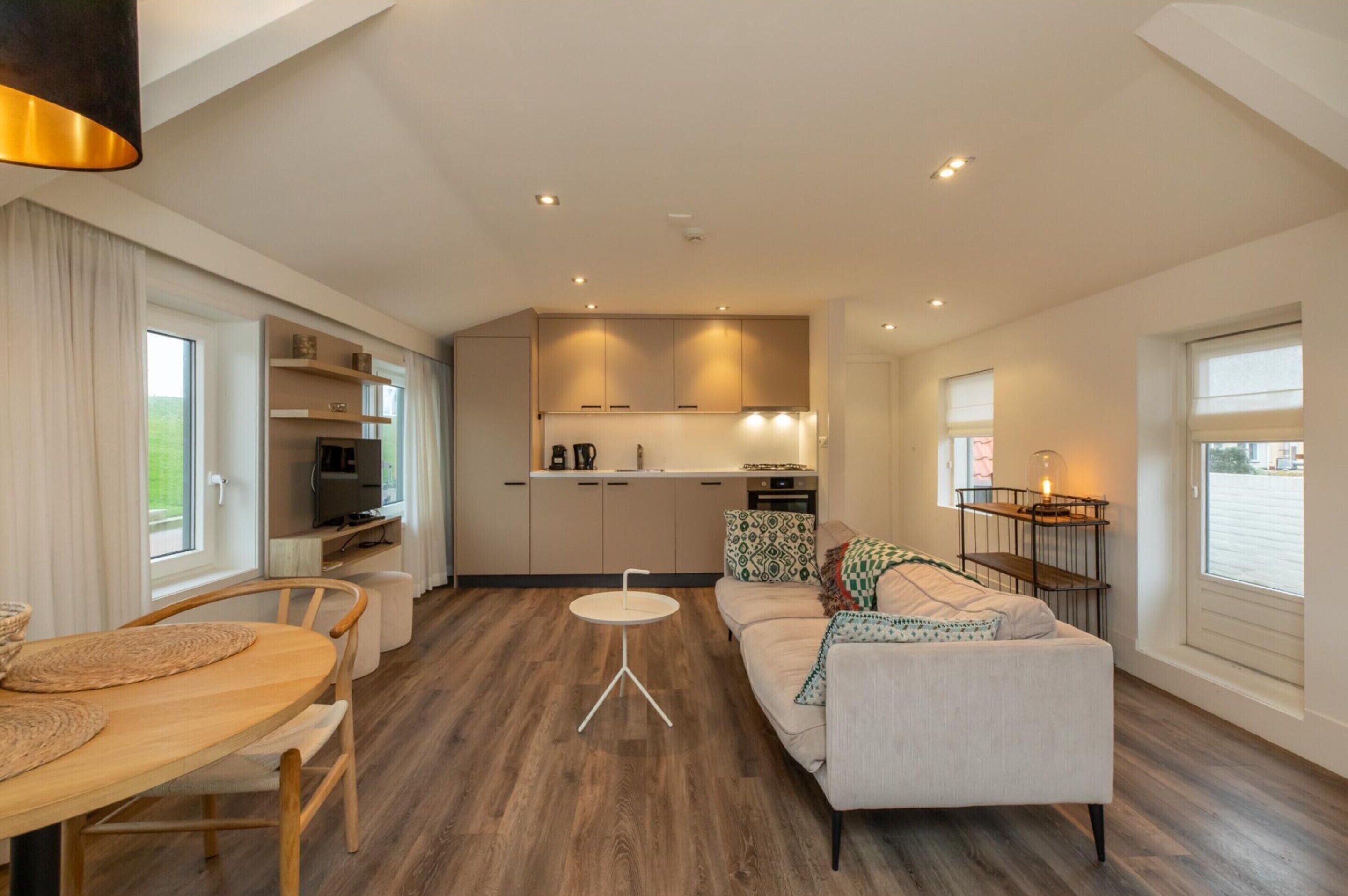 Una sala de estar moderna con un sofá, una mesa de comedor y una cocina equipada.