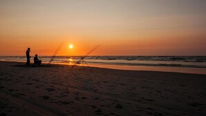 A beach scene at sunset with two people fishing. - Cozy Chalet in Tzummarum (Tzummarum)