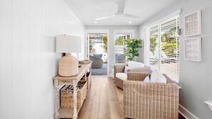 A hallway with wicker furniture, a ceiling fan, and a view to the outside. - Book Magnolia Shores: Family-Friendly Getaway Near Beach with Pool and Mini Golf (Anna Maria)